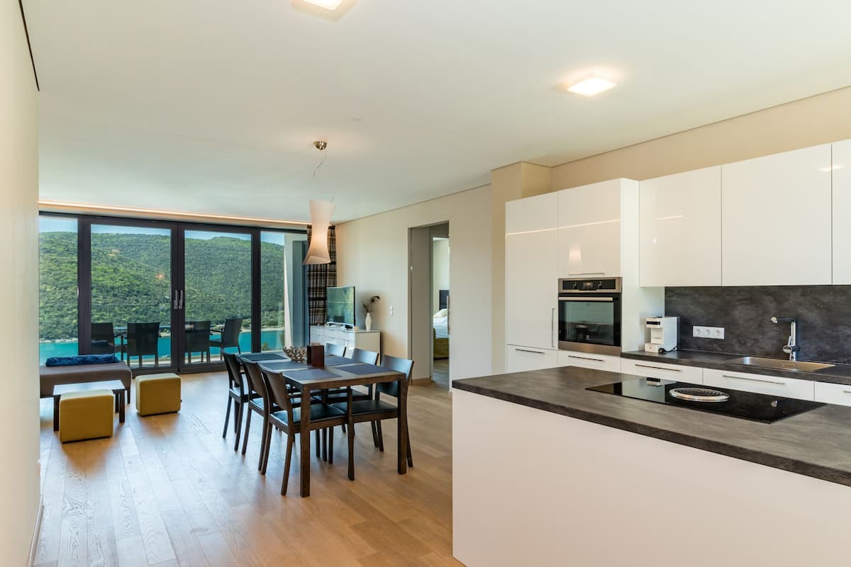 A modern kitchen with a large island, wooden dining table, and chairs.