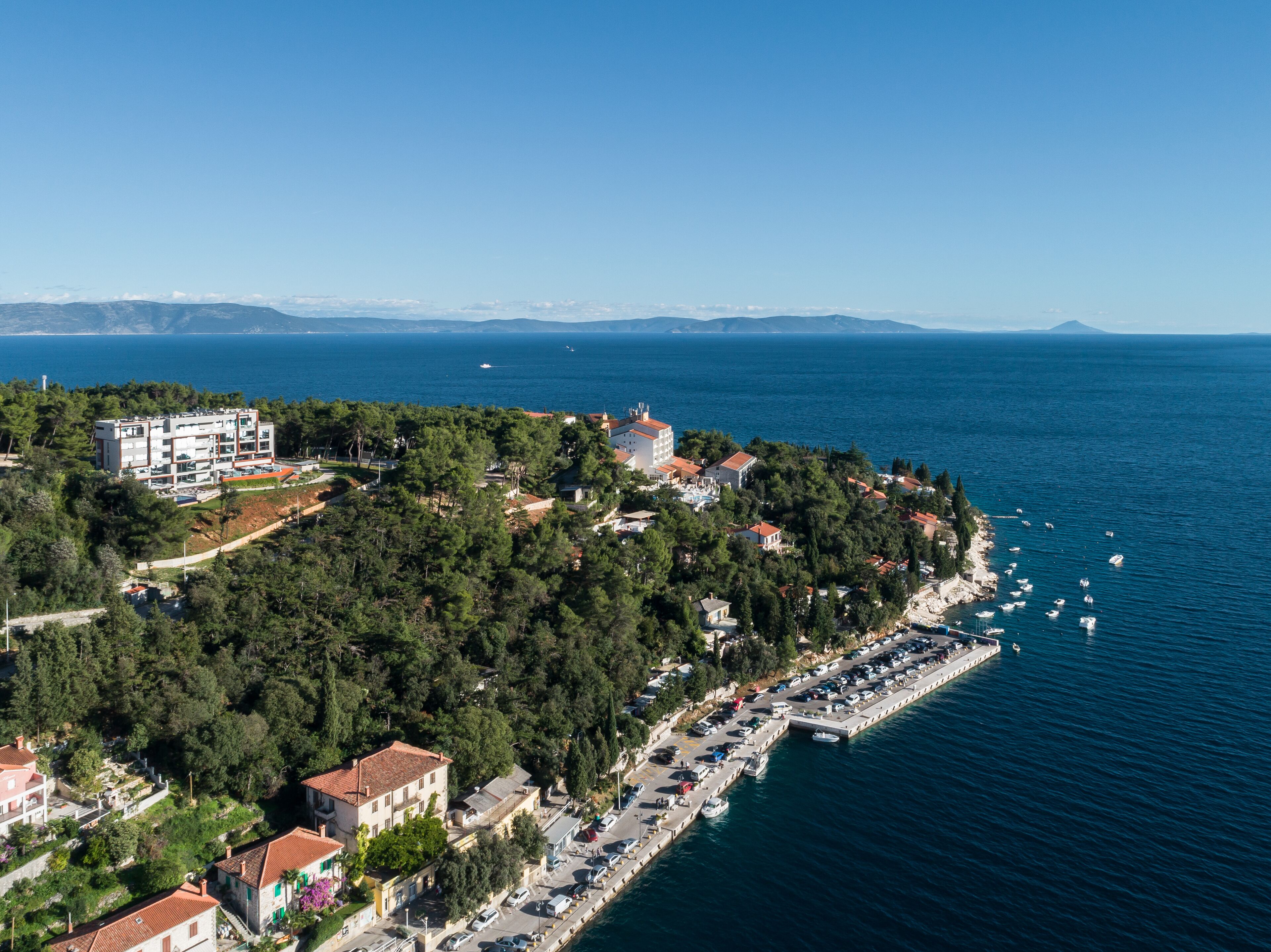 A coastal town with a marina, residential buildings, and a clear view of the sea.