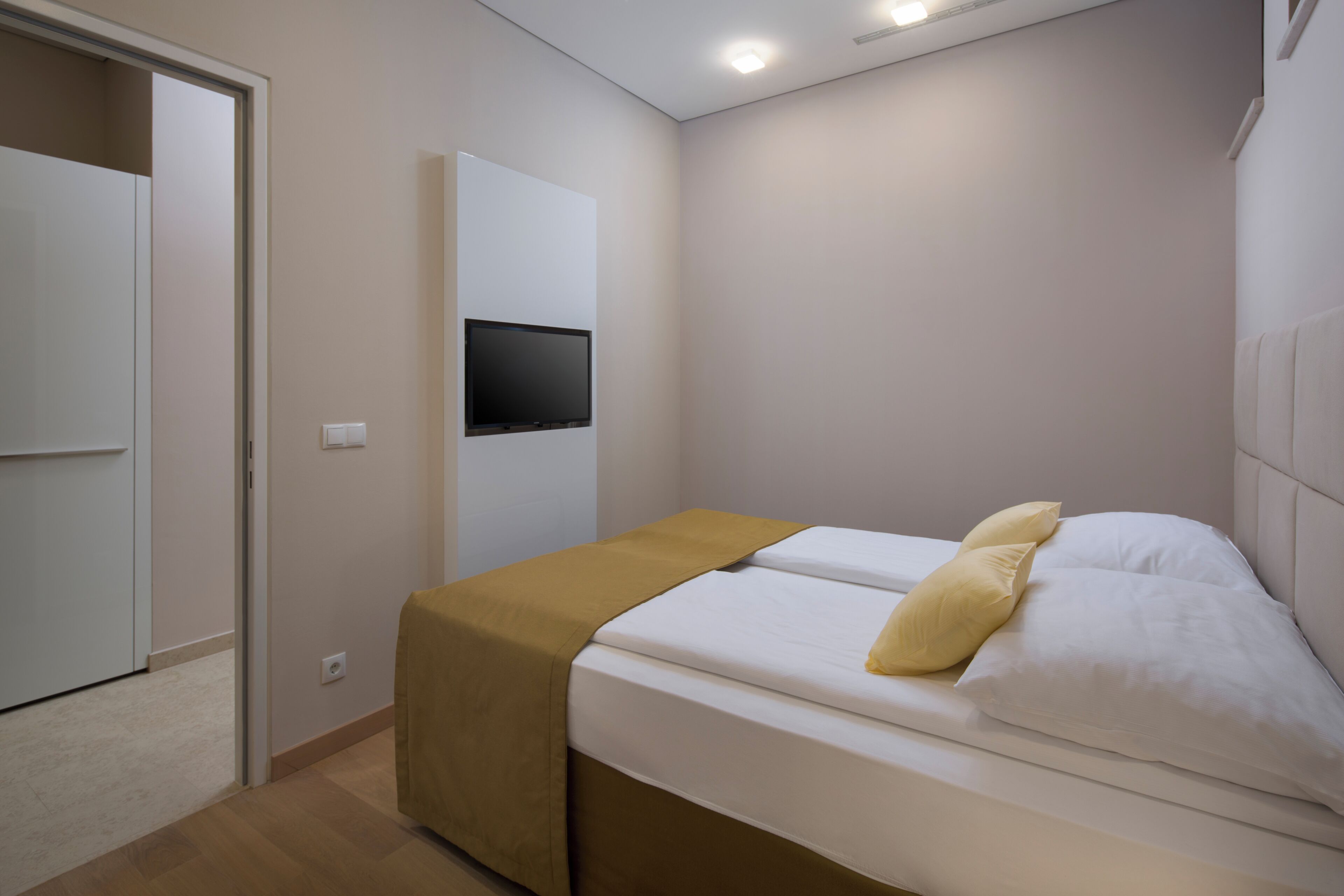 Une chambre à coucher avec un lit, un téléviseur fixé au mur et une armoire.