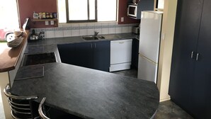 Een kleine keuken met een vaatwasser, een magnetron en een koelkast.