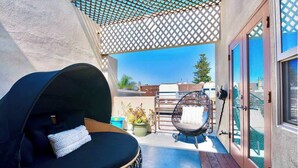 Ein Balkon mit Korbstuhl, Hängesessel und Topfpflanze.