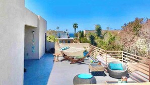 Eine Dachterrasse mit Hängematte, Sitzgelegenheiten und einem Pool.
