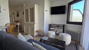 Een woonkamer met een bank, een bijzettafeltje, een televisie en een raam met uitzicht.