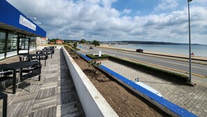 Hotel con terraza al aire libre con vista a una carretera y una playa.
