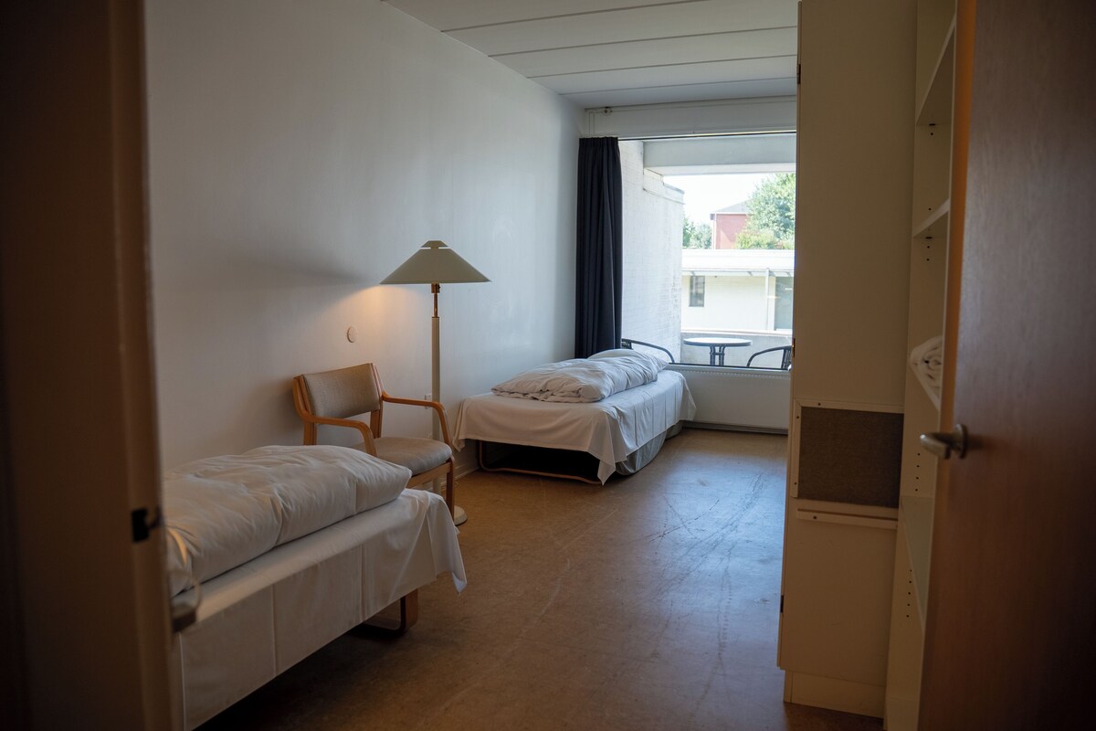 A room with two single beds, a chair, and a table.