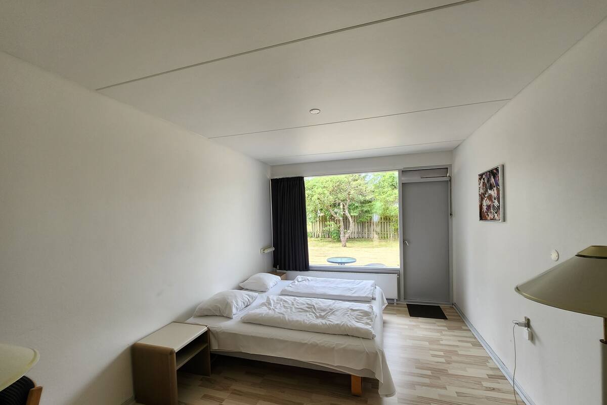 Un dormitorio con cama, mesita de noche y vistas al exterior.