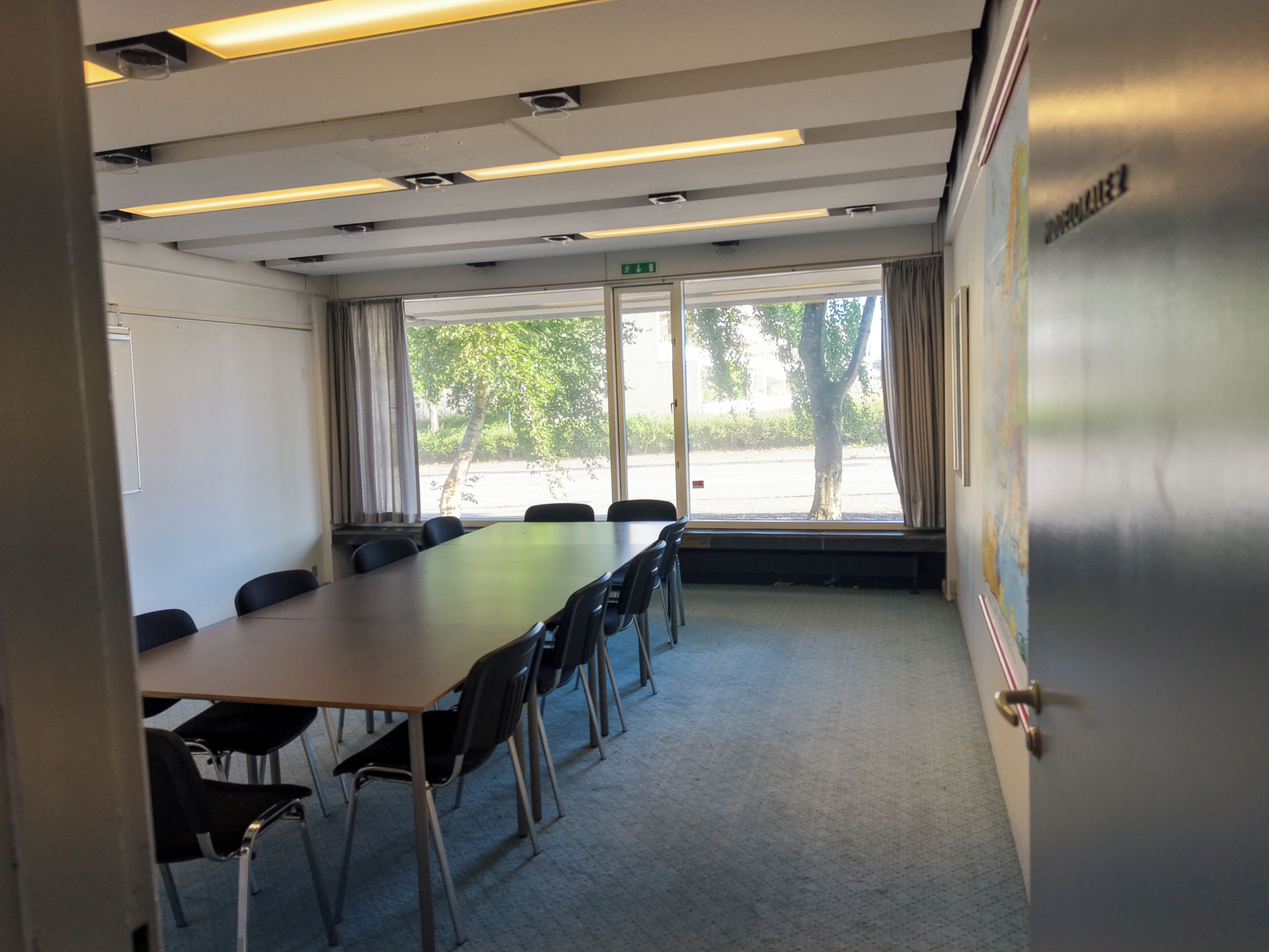 A conference room with a long table, chairs, and large windows.