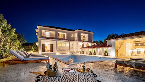 A two-story house with a swimming pool, outdoor seating, and a well-lit patio area. - Aigli Villa (Zakynthos)