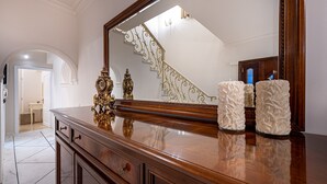 A wooden dresser with a large mirror, two white candles, and a gold decorative item. - Aigli Villa (Zakynthos)