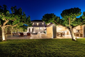 Enjoy a spacious outdoor area with a well-maintained lawn, lounge chairs, and dining table.