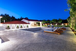 Relax by the pool surrounded by lush greenery and comfortable seating.