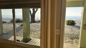 A beach view from a room with a window, a chair, and a sign indicating no swimming. - Totally Remodeled Beachfront Studio-Step out your door onto the sand. Really! D (Bradenton Beach)