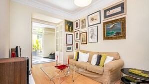 Ein Wohnzimmer mit einem beigefarbenen Sofa, einem Glastisch und einem Bücherregal.