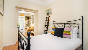 Ein Schlafzimmer mit einem Bett, einem Bücherregal und einer Tür zu einem anderen Raum.
