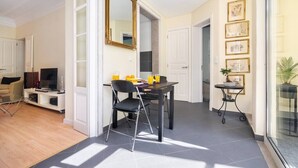 Ein modernes Wohnzimmer mit Essbereich, einem großen Spiegel und einem kleinen Tisch mit Pflanze.