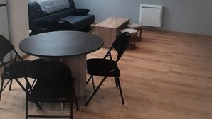 Une pièce comprenant une table ronde, quatre chaises, un canapé, un meuble et un radiateur.