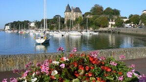 Un puerto con barcos, un castillo y un parterre de flores.
