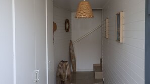 Una escalera con una lámpara de fibra, una puerta de madera y un espejo fijado a la pared.
