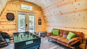 Ein gemütliches Zimmer mit Tischfußball, einer Ledersofa mit grünen Kissen und einer Dartscheibe an der Wand.