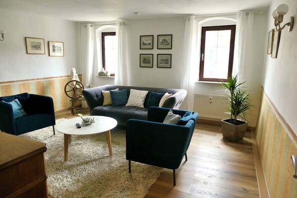 Un salon comprenant un canapé, deux fauteuils, une table basse et une plante en pot.