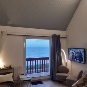 Une chambre avec vue sur la mer, un lit, un bureau, une chaise et un téléviseur fixé au mur.
