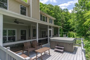 A two-story house with a covered porch, outdoor seating, and a hot tub.