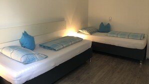 Een kamer met twee bedden, elk met een hoofdeinde, en een hanglamp.