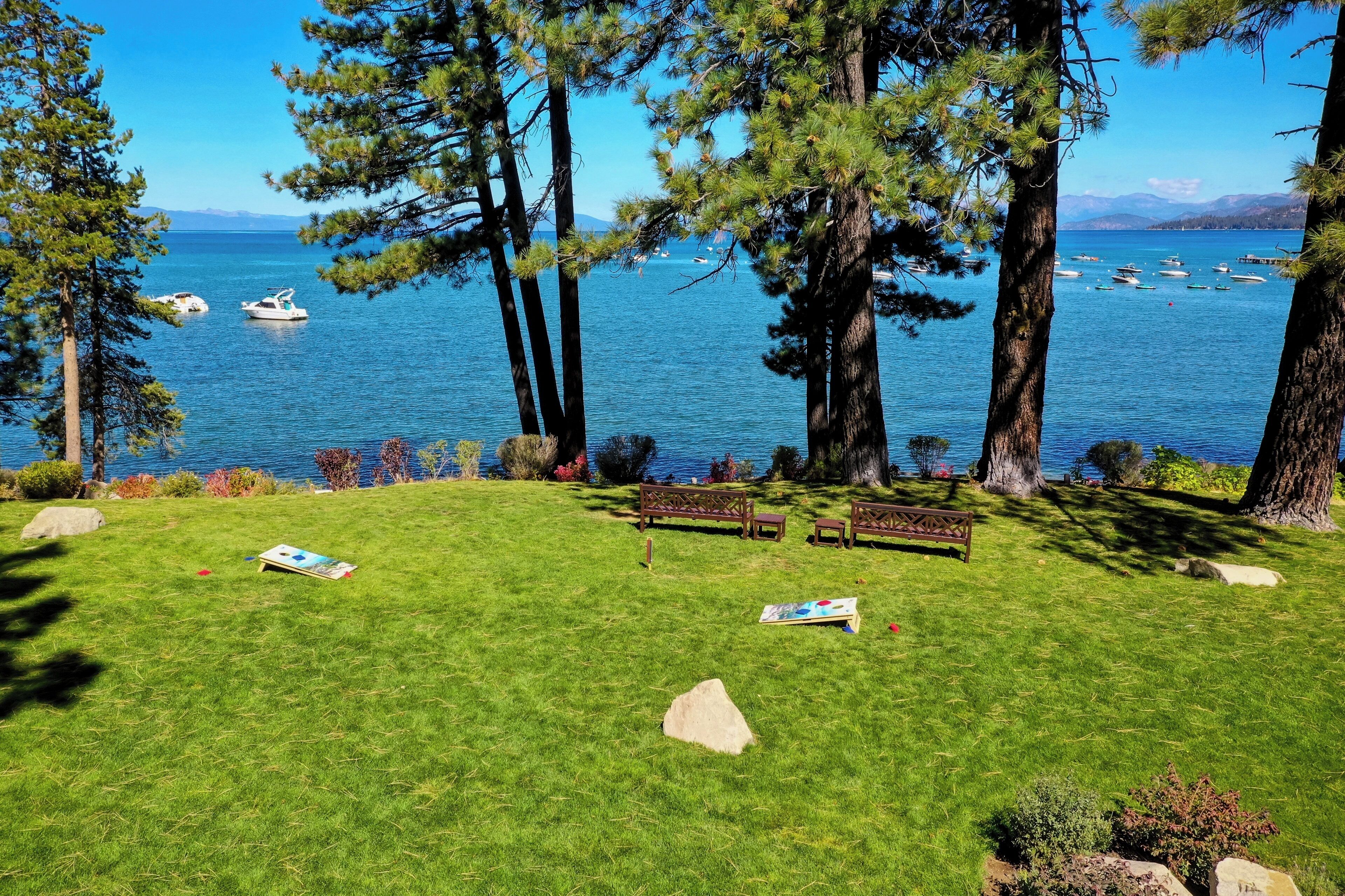 Un espace verdoyant avec des bancs et une vue sur un lac où l’on peut voir des bateaux.