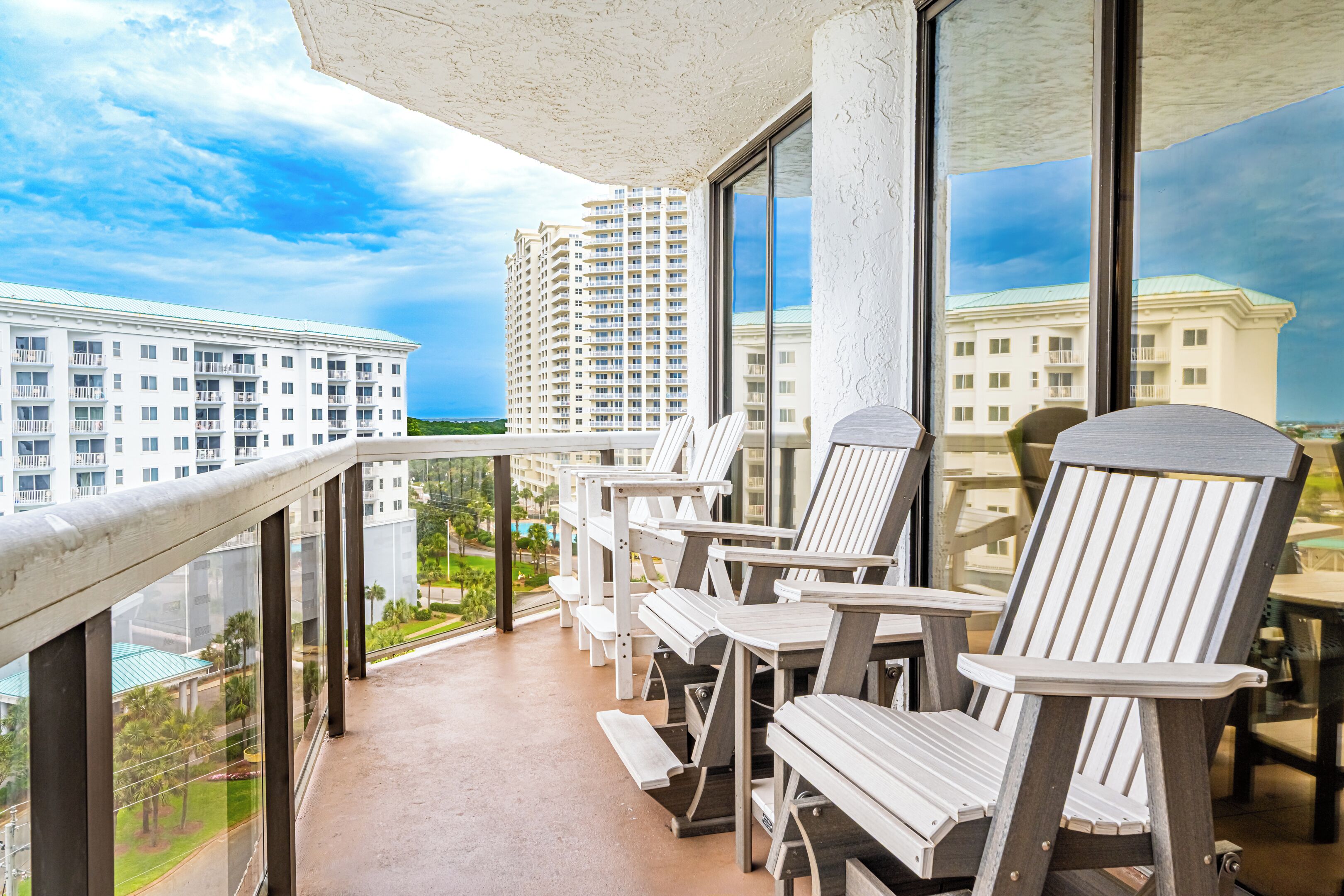 A balcony with outdoor seating, large windows, and a view of high-rise buildings.