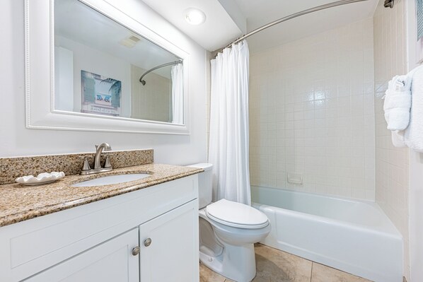 A bathroom with a sink, mirror, toilet, and shower.