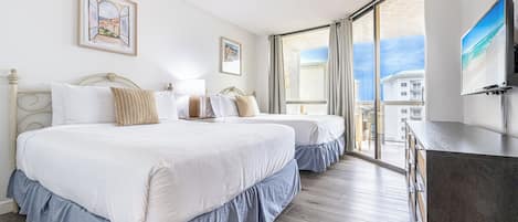 A hotel room with two beds, a large window, and a flat-screen TV.