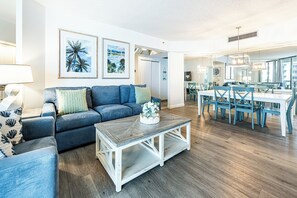 A modern living room with a sofa, coffee table, and dining area with chairs and a table.