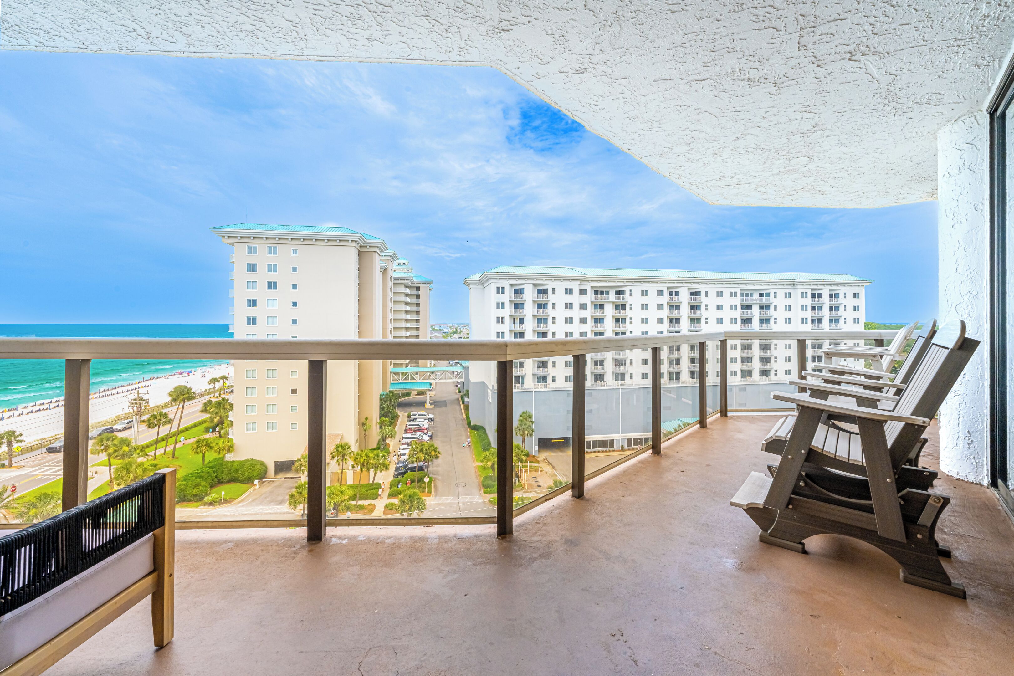 Een balkon met uitzicht op een strand en hotelgebouwen.