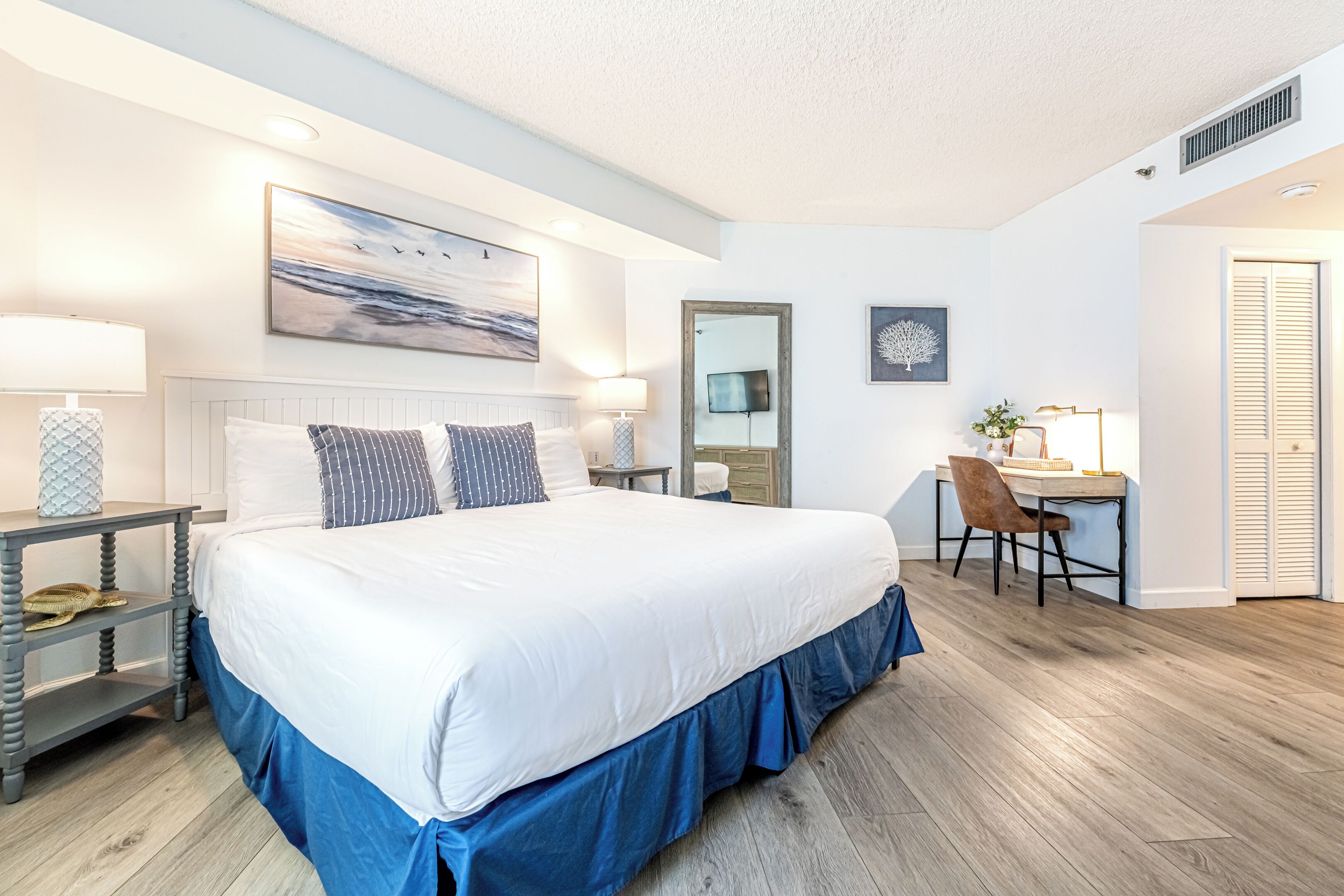 A bedroom with a large bed, bedside tables, a desk, and a chair.