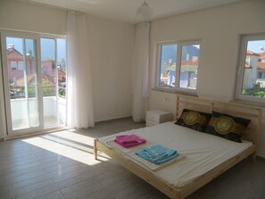 Enjoy a restful night's sleep in this serene bedroom with a comfortable bed, large windows, and a convenient bedside table.