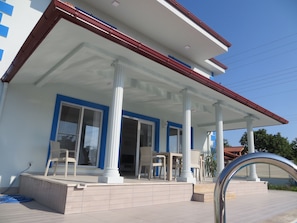 Stylish porch with columns, windows, and a flat roof, set amidst a beautifully paved area.