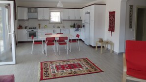 Una cocina moderna con armarios blancos, una mesa de comedor con sillas rojas y una alfombra roja estampada.