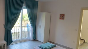 Un dormitorio con cama, armario y ventana con cortinas.