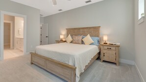 A bedroom with a bed, nightstands, a ceiling fan, and a door to another room. - New Build • Walk to the beach• Bikes • Beach Toys! (St. Augustine)