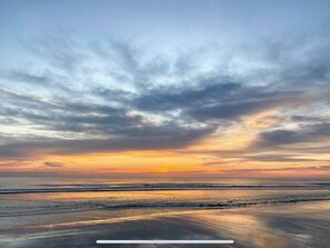 Una spiaggia con un tramonto e onde calme.