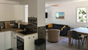 Une cuisine moderne dotée d’une cuisinière intégrée, un coin repas avec une table et des chaises, un canapé et un tableau accroché au mur.