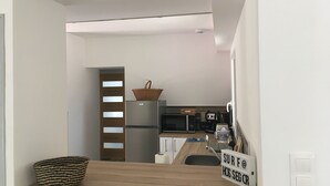 Une cuisine moderne avec un plan de travail en bois, un réfrigérateur en acier inoxydable, un four à micro-ondes et un grille-pain. On peut voir un panier sur le réfrigérateur et un panneau sur le mur.