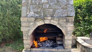 Un horno para pizza de piedra con fuego encendido en su interior.