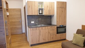 A compact kitchen with wooden cabinets, a stainless steel sink, and a built-in oven.