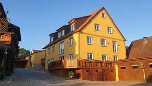 A multi-story building with a yellow facade, wooden balconies, and a cobblestone street.
