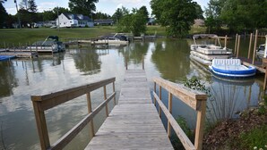 A wooden dock leading to a calm lake with boats docked on the shore. - Lakeside living awaits at beautiful Lake Milton, OH
 with dock across the street (Lake Milton)