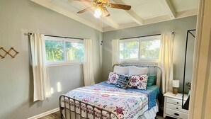 A bedroom with a bed, a nightstand, a ceiling fan, and two windows with curtains. - Lakeside living awaits at beautiful Lake Milton, OH
 with dock across the street (Lake Milton)