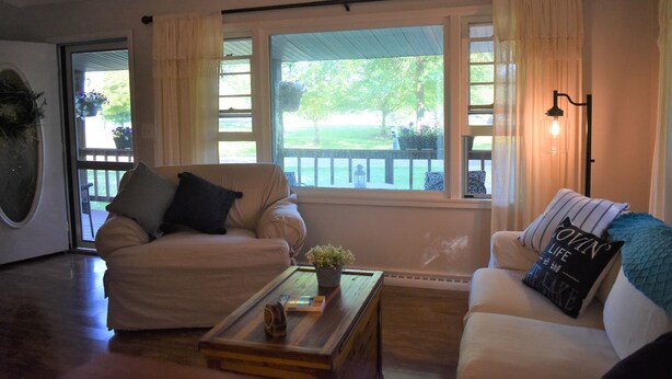 A living room with two sofas, a coffee table, and a large window with curtains. - Lakeside living awaits at beautiful Lake Milton, OH
 with dock across the street (Lake Milton)
