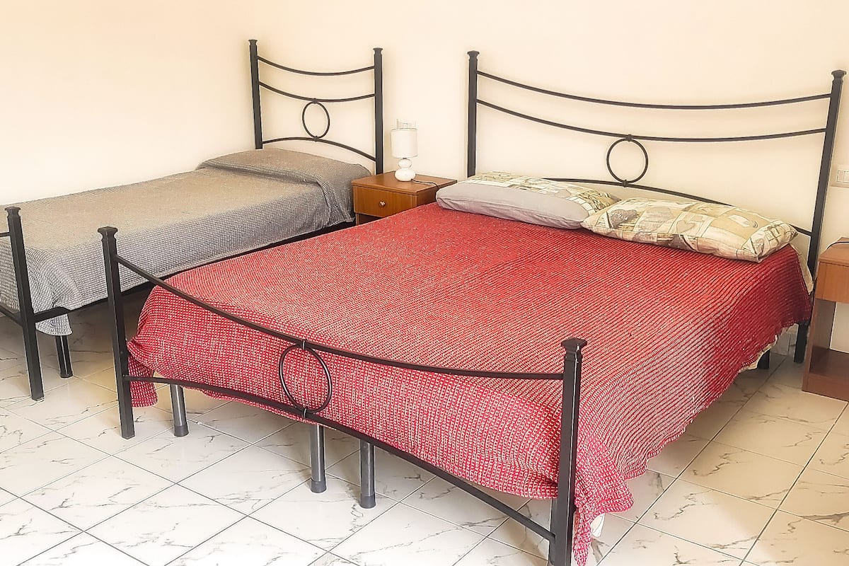 Two single beds with metal frames, a small wooden nightstand, and a chair.
