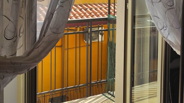A sliding glass door with a view of a balcony and a yellow wall. - Hippocampus B&B (Giardini Naxos)